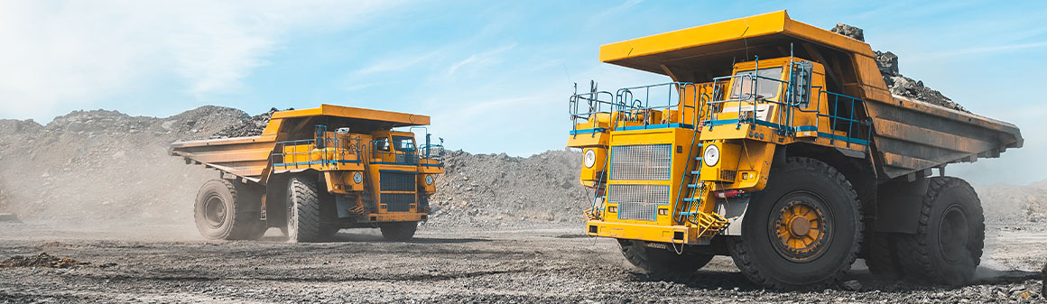 Két sárga bánya teherautó egy bányában leparkolva