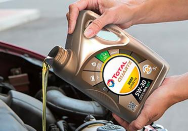 Egy autós Total Quartz olajat ad az autó motorjához